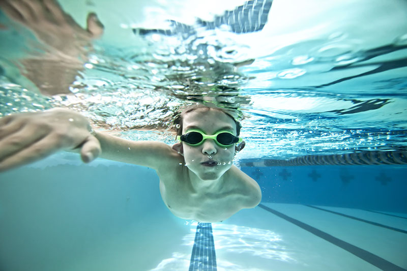 boy swimming underwater after swim class