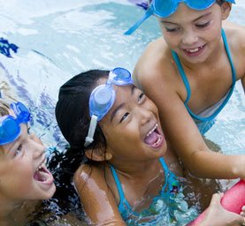 three kids hanging out in the pool after swim class in Fredericksburg